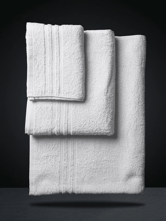 Set di 3 asciugamani bianchi in puro cotone per hotel, linea Classic, piegati e impilati su sfondo scuro